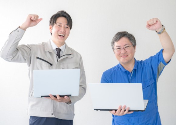 ノートパソコンを持ってガッツポーズをする社員
